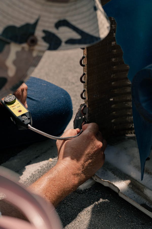 HVAC technician using an electronic leak detector on a coil