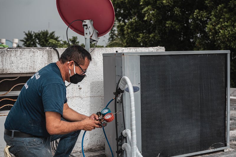 HVAC technician diagnosing a condenser with manifold gauges
