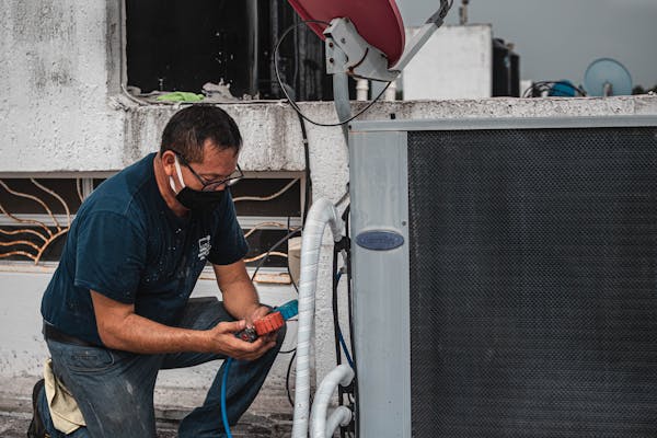 HVAC technician servicing a condenser unit during installation