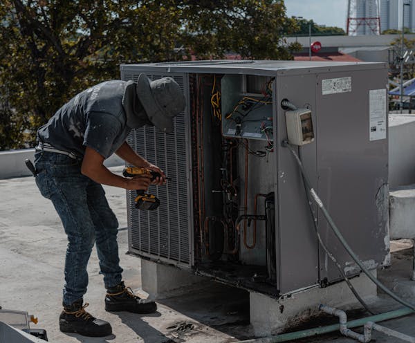HVAC technician performing maintenance on rooftop equipment