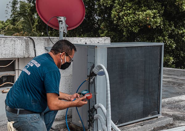 HVAC technician checking refrigerant gauge readings on a condenser unit